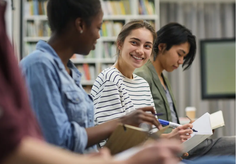 three students smiling in a library