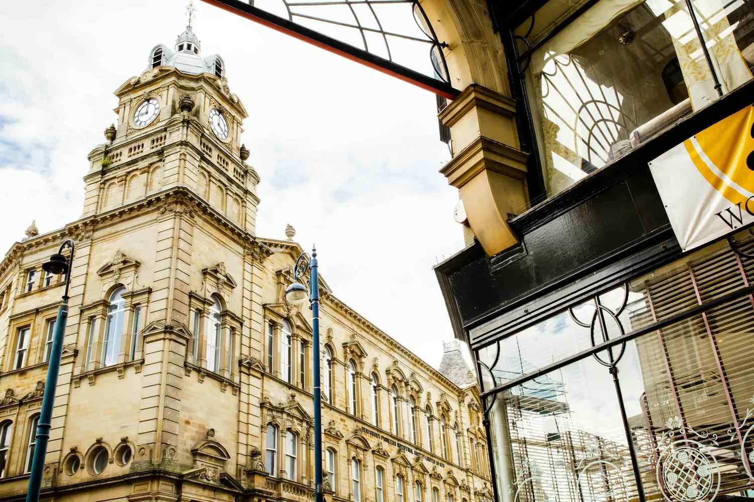 Historic building with clock tower next to modern glass structure, reflecting architectural evolution. Ideal for studying urban development and historical preservation.