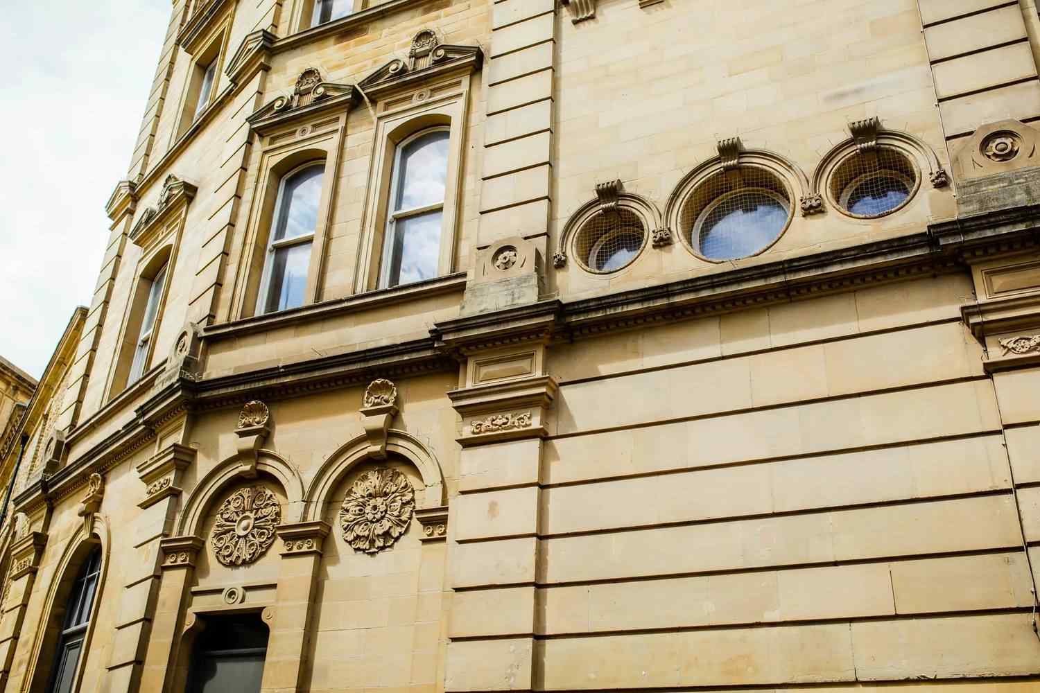 Historic stone building with ornate windows and decorative carvings, showcasing classical architectural style, ideal for educational inspiration.