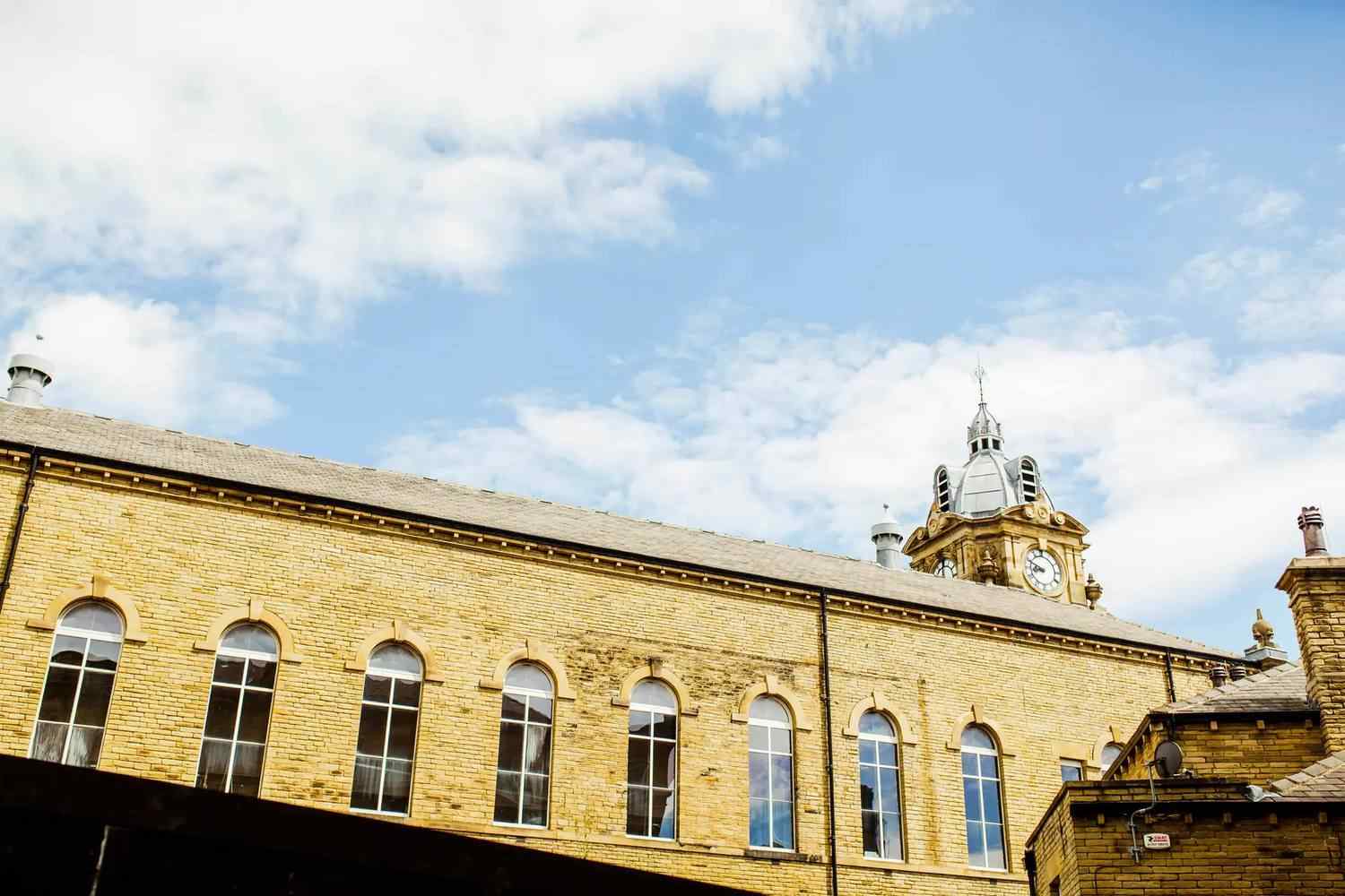 A historic college building with arched windows and a clock tower under a blue sky.