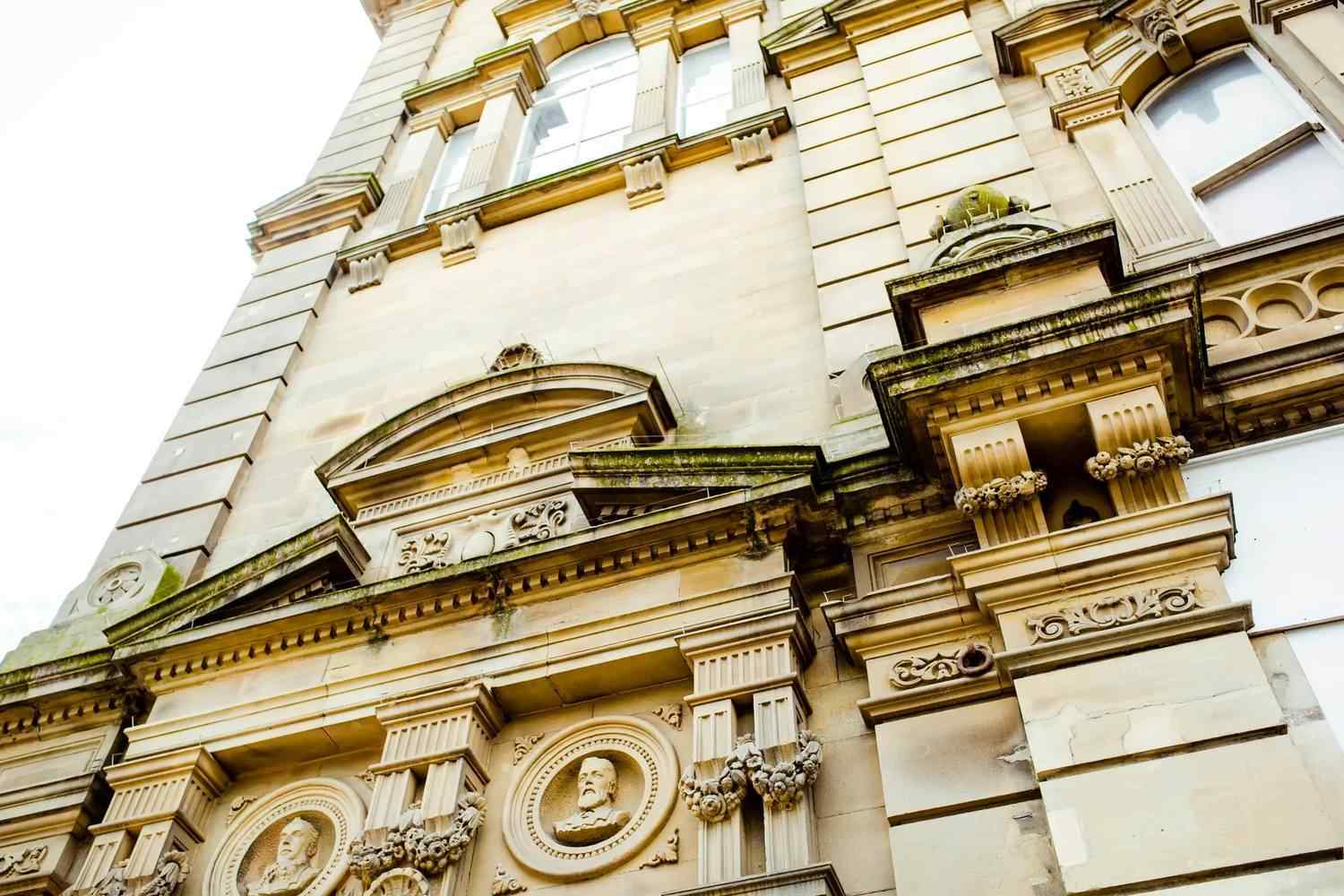Historic building facade with ornate stonework, columns, and busts, showcasing classical architectural elements. Ideal for educational context on architecture.