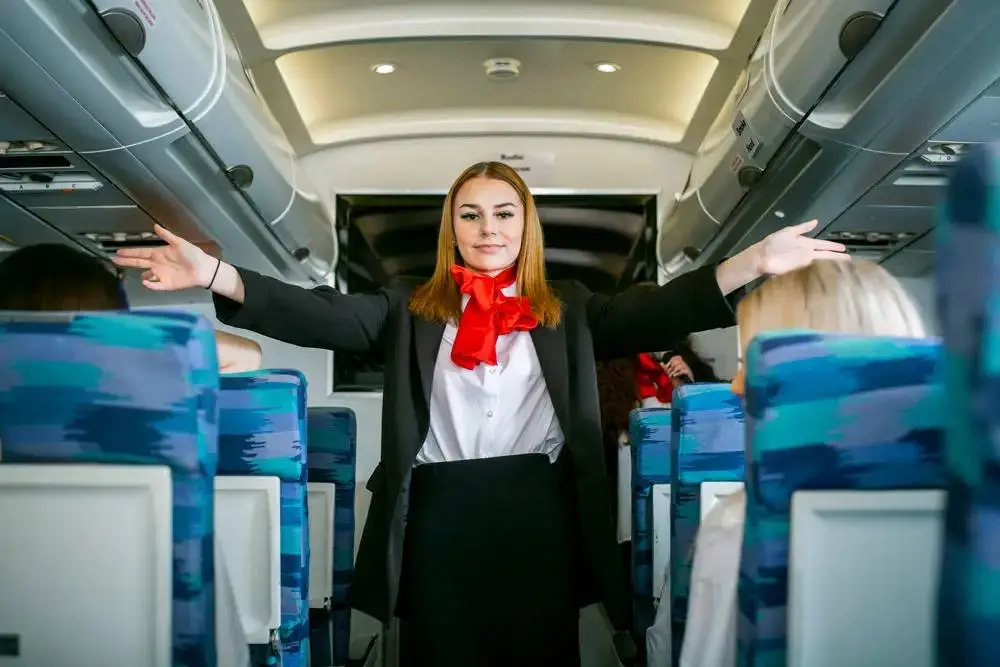 Flight attendant in uniform demonstrating safety procedures on an aeroplane.