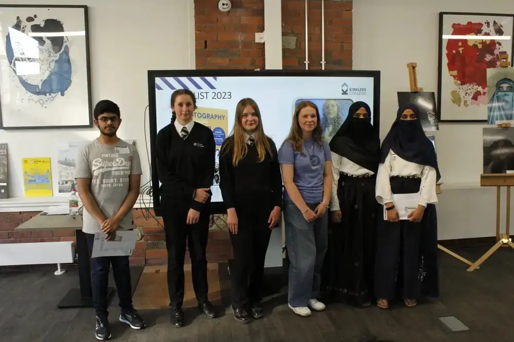Group of students posing in front of a screen displaying Art