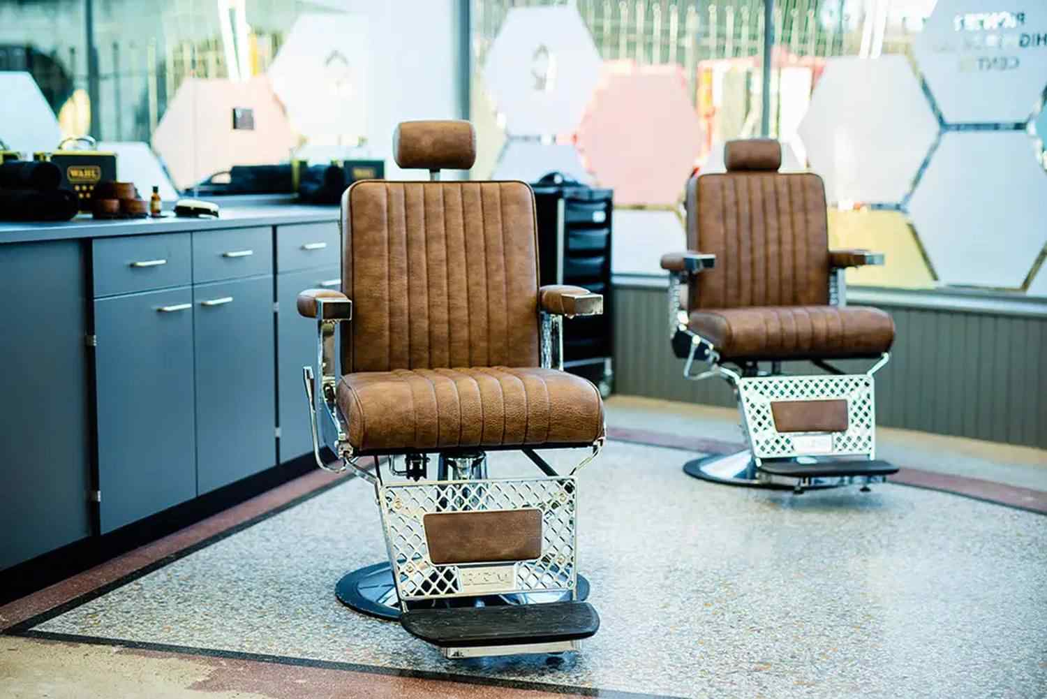 Two vintage barber chairs in a modern salon with polished floors and stylish decor, reflecting traditional grooming practices in a contemporary educational setting.