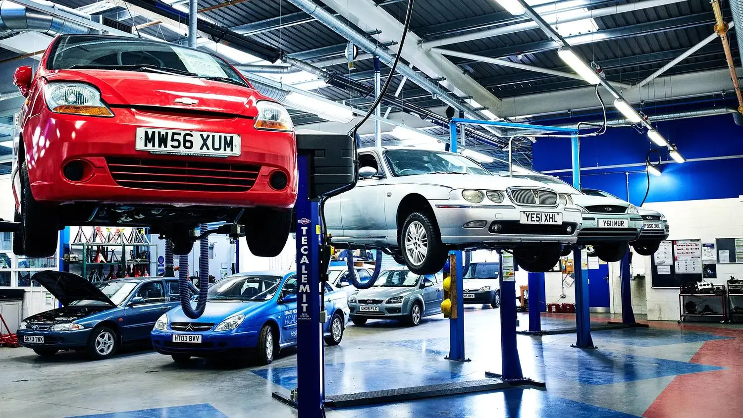 A college automotive workshop with cars on lifts, showcasing practical engineering and vehicle maintenance training.
