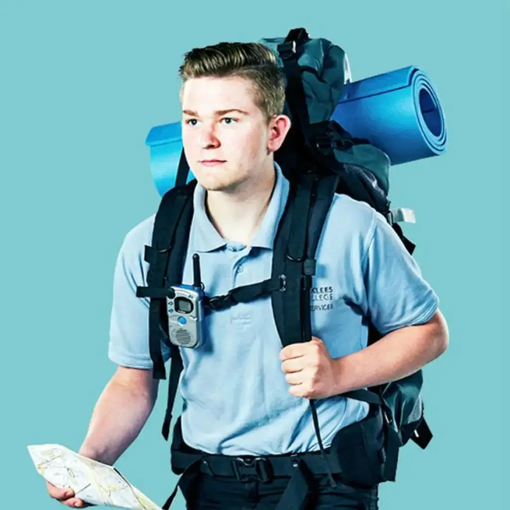 A student in a light blue polo shirt with a large backpack and map, ready for an outdoor adventure or field study.
