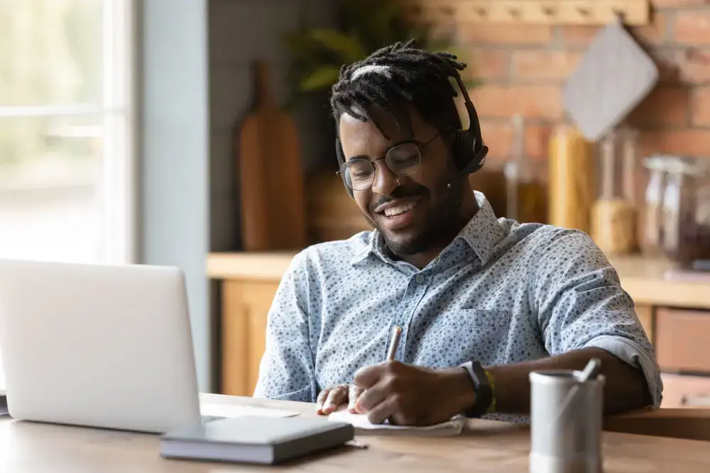 Smiling biracial man in headphones study online on computer