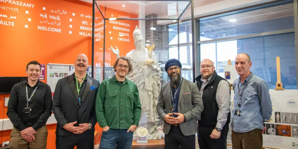Staff and artist pose in front of picture