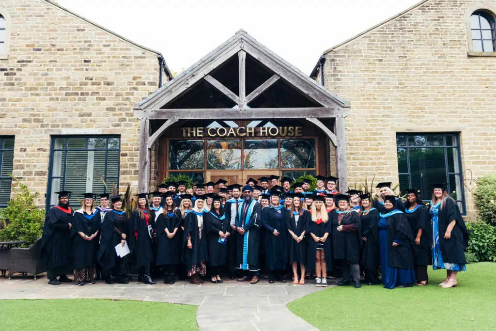 group of students and staff all in graduation attire in front of the Coach House venue