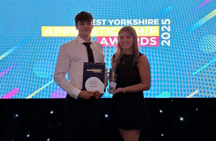 Kirklees College apprentices pose with awards in front of screen at West Yorkshire Apprenticeship Awards