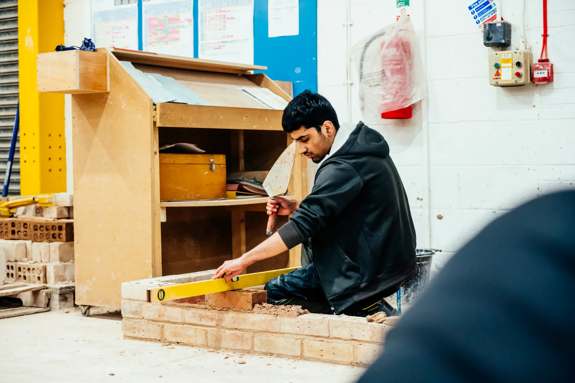 Student uses a spirit level on a brick wall
