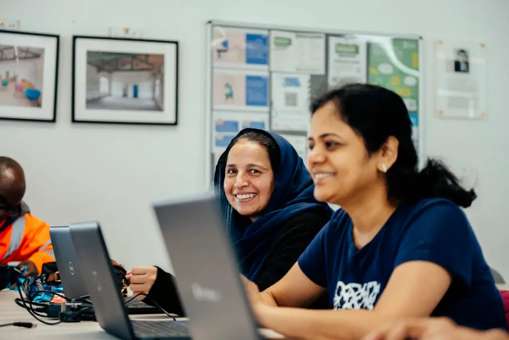 Two women work on laptops