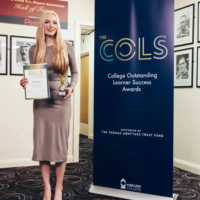 A woman in a grey dress holding a certificate and trophy next to a blue banner for the College Outstanding Learner Success Awards.