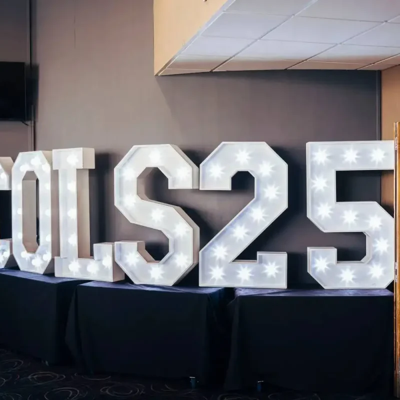 Illuminated COLS25 sign on tables, celebrating 25 years of college education excellence.