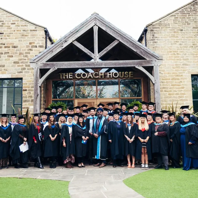 Graduates in academic gowns and caps pose in front of The